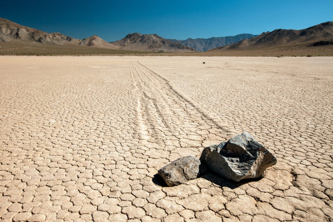 a cracked desert landscape with two stones