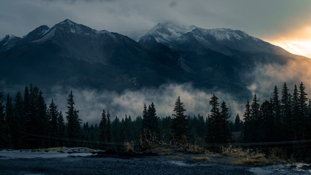 Low clouds hang at the base of a towering mountain range