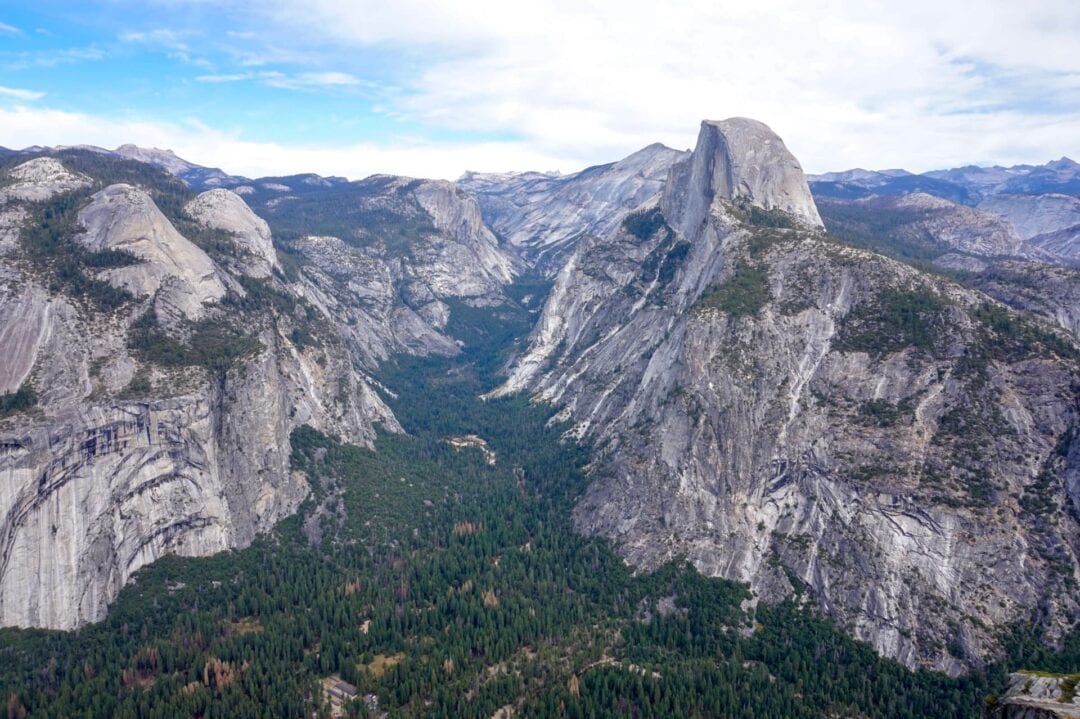 Large mountain range towering over a green valley at Yosemite National Park